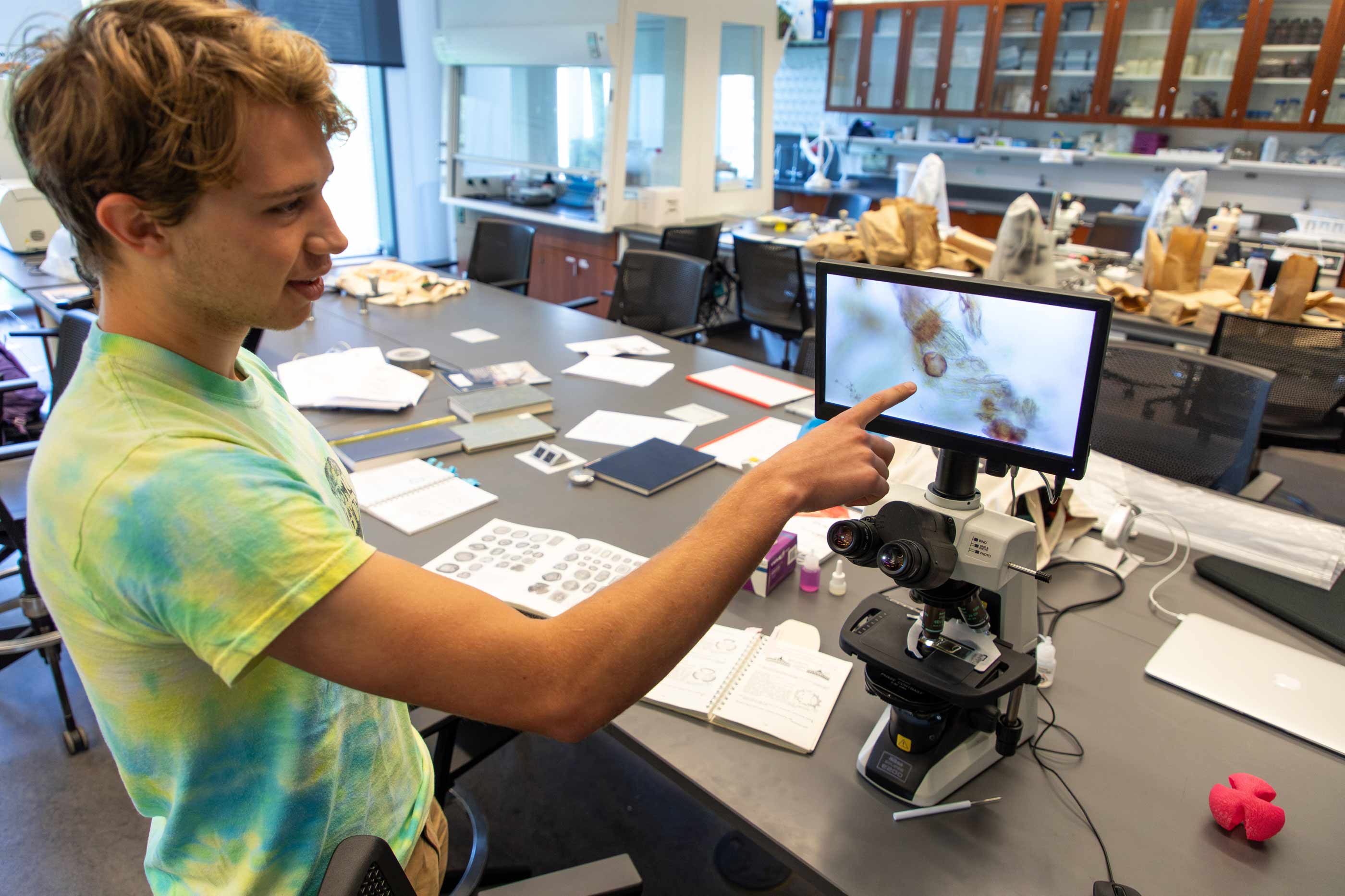 Ezra Potts ’25 points to a screen showing what pollen looks like when viewed under a microscope.