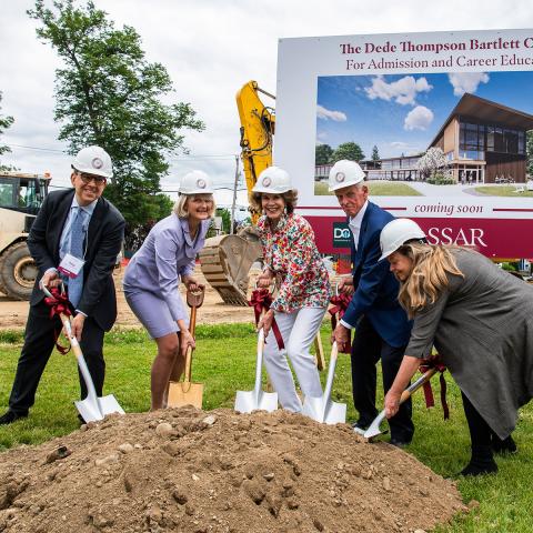 Five people standing outside with shovels and hardhats digging the ceremonial first scoop. 