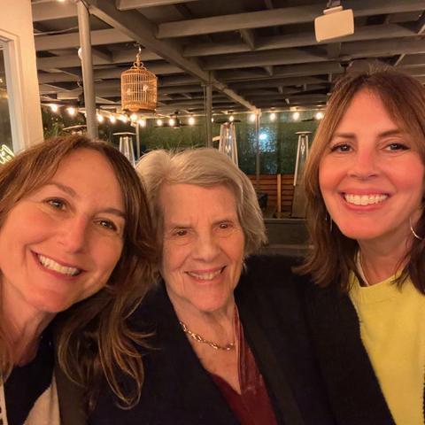 Three women, smiling, wearing black jackets.