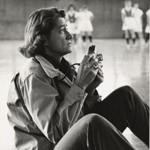 Black and white photo of a person seated on the floor holding a camera.